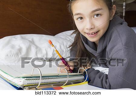 Mixed race girl doing homework on bed View Large Photo Image Stock Image - Mixed race girl doing homework on bed. Fotosearch