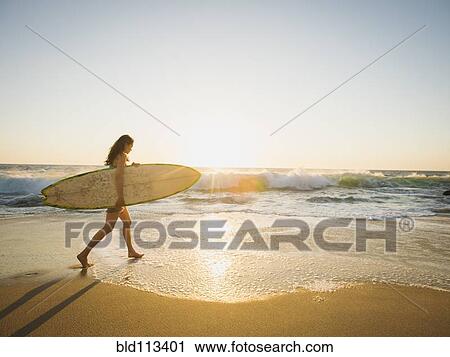 Mixed race woman carrying surfboard on beach View Large Photo Image Stock Image - Mixed race woman carrying surfboard on beach. Fotosearch