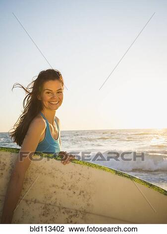 Mixed race woman carrying surfboard on beach View Large Photo Image Stock Image - Mixed race woman carrying surfboard on beach. Fotosearch
