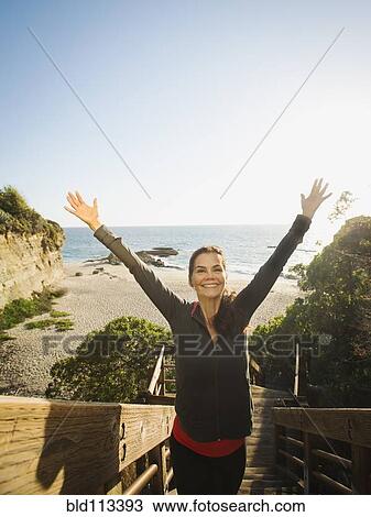 Stock Image - Mixed race woman climbing steps on beach. Fotosearch
