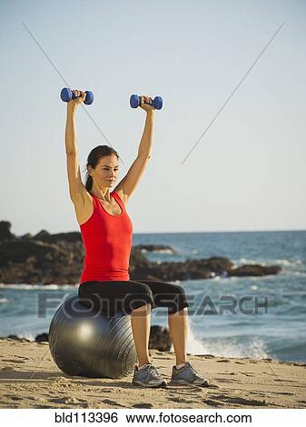 Stock Photograph - Mixed race woman exercising on beach. Fotosearch