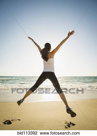Mixed race woman jumping for joy on beach View Large Photo Image Stock Image - Mixed race woman jumping for joy on beach. Fotosearch