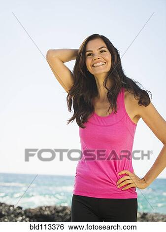 Stock Photograph - Mixed race woman smiling on rocky beach. Fotosearch