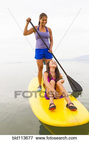 Mother and daughter riding paddle board View Large Photo Image Stock Photo - Mother and daughter riding paddle board. Fotosearch