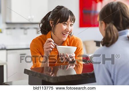 Stock Photography - Mother and daughter talking in kitchen. Fotosearch