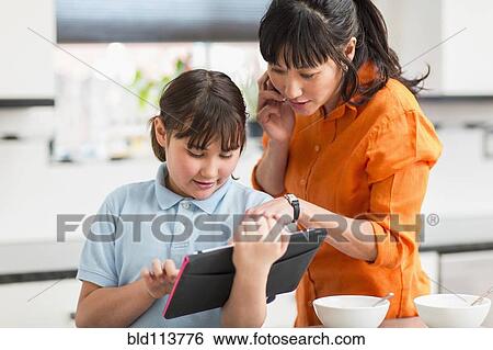 Stock Photograph - Mother and daughter using tablet computer. Fotosearch