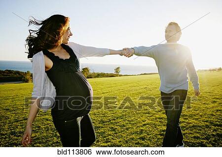 Pregnant couple playing in field View Large Photo Image Stock Photograph - Pregnant couple playing in field. Fotosearch