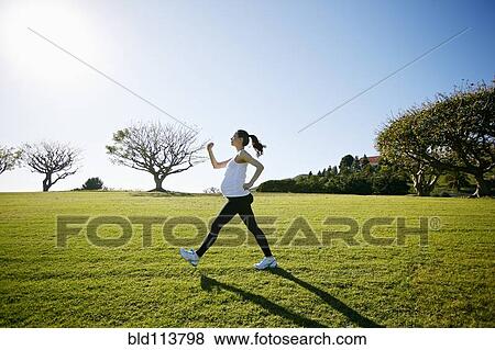 Stock Photo - Pregnant mixed race woman exercising in field. Fotosearch