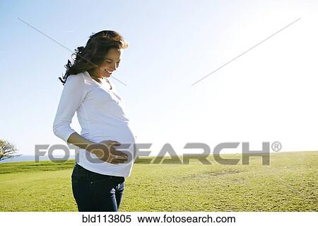 Stock Photography - Pregnant mixed race woman holding her belly. Fotosearch
