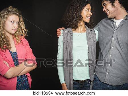 Smiling couple ignoring friend View Large Photo Image Picture - Smiling couple ignoring friend. Fotosearch
