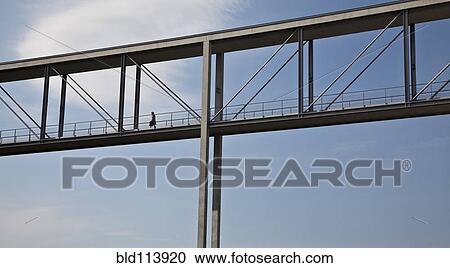 Stock Image - Woman walking on skybridge, Berlin, Germany. Fotosearch