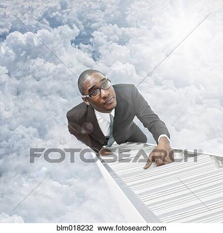 Stock Image - African American businessman climbing ladder. Fotosearch