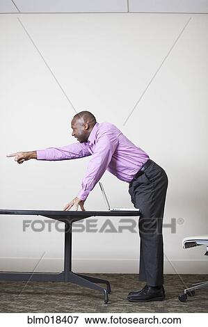 Stock Photo - African American businessman leaning over desk. Fotosearch