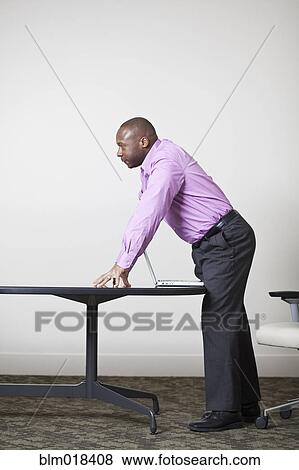 Stock Photo - African American businessman leaning over desk. Fotosearch