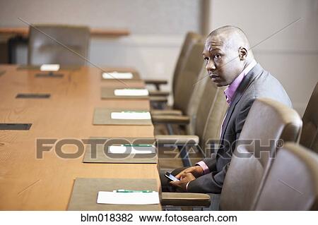 Stock Image - African American businessman sitting at meeting table. Fotosearch