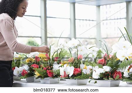 Stock Photo - African American businesswoman arranging flowers. Fotosearch