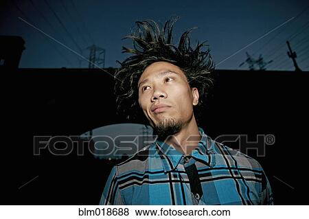 Stock Photo - Asian man standing under overpass. Fotosearch