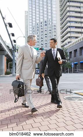 Businessmen walking together on city street View Large Photo Image Stock Image - Businessmen walking together on city street. Fotosearch
