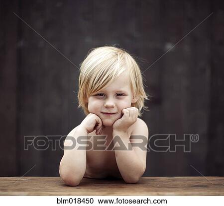 Stock Image - Caucasian boy sitting at table outdoors. Fotosearch
