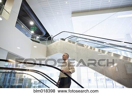 Caucasian businessman standing on escalator View Large Photo Image Stock Photo - Caucasian businessman standing on escalator. Fotosearch