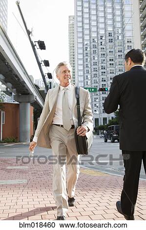 Stock Image - Caucasian businessman walking on city street. Fotosearch