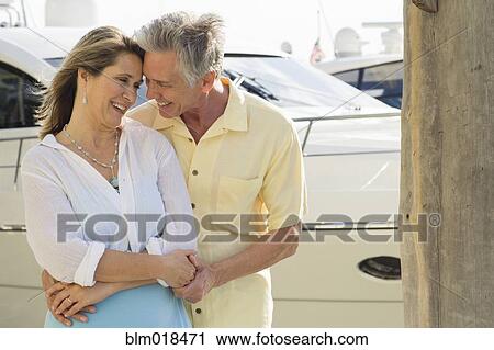 Stock Image - Caucasian couple hugging on dock. Fotosearch
