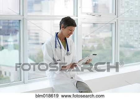 Stock Photo - Caucasian doctor reading using tablet computer. Fotosearch