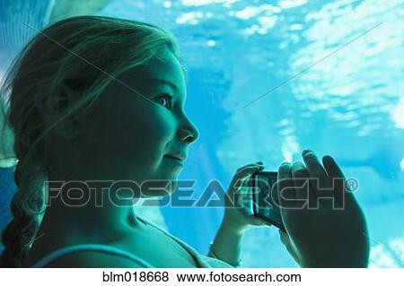 Stock Photo - Caucasian girl taking pictures in aquarium. Fotosearch