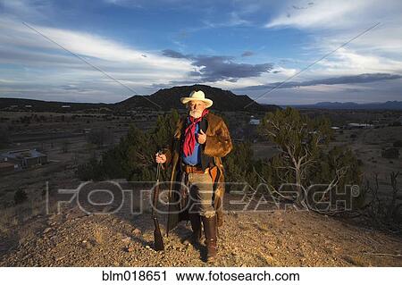 Caucasian man holding gun in dusty landscape View Large Photo Image Stock Image - Caucasian man holding gun in dusty landscape. Fotosearch
