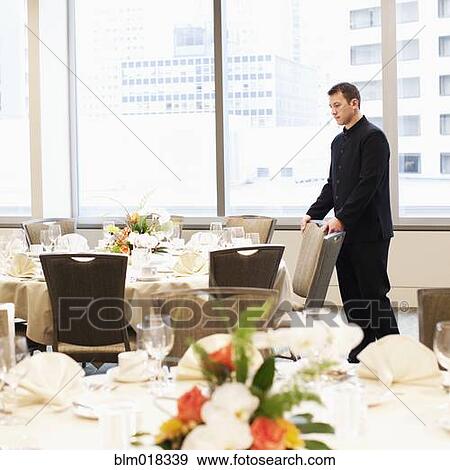 Caucasian waiter setting chairs in dining room View Large Photo Image Stock Photo - Caucasian waiter setting chairs in dining room. Fotosearch