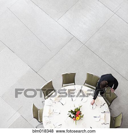 Caucasian waiter setting table in dining room View Large Photo Image Stock Photo - Caucasian waiter setting table in dining room. Fotosearch