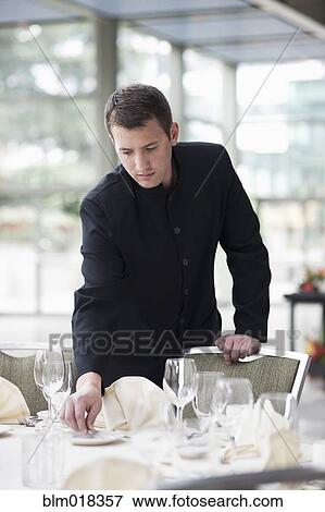 Caucasian waiter setting tables in dining room View Large Photo Image Stock Photo - Caucasian waiter setting tables in dining room. Fotosearch