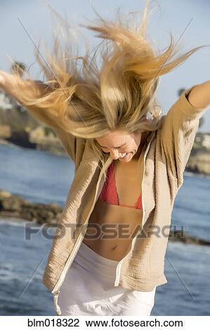 Stock Image - Caucasian woman dancing at beach. Fotosearch