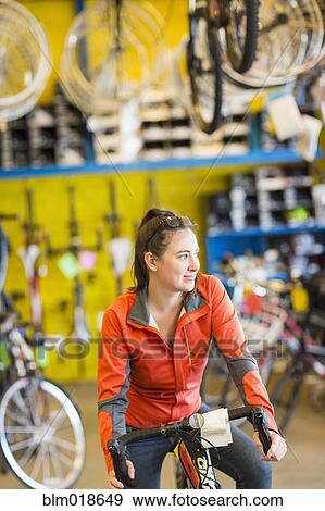 Stock Photo - Caucasian woman sitting in bicycle shop. Fotosearch