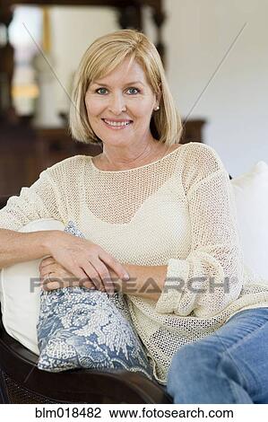 Stock Image - Caucasian woman smiling on sofa. Fotosearch
