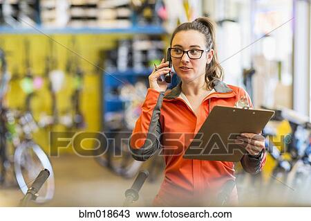 Caucasian woman talking on telephone in bicycle shop View Large Photo Image Stock Image - Caucasian woman talking on telephone in bicycle shop. Fotosearch