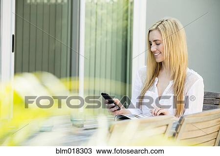 Stock Image - Caucasian woman using cell phone outdoors. Fotosearch