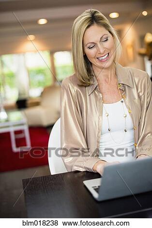 Stock Photo - Caucasian woman using laptop at desk. Fotosearch