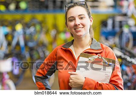 Picture - Caucasian woman with clipboard in bicycle shop. Fotosearch