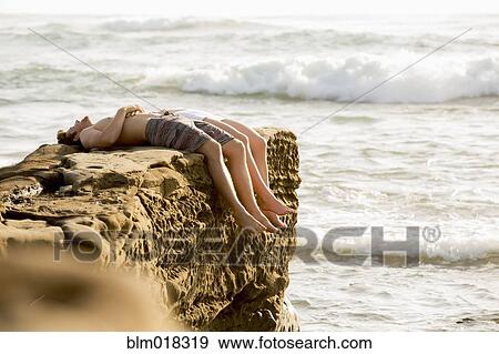 Stock Photo - Couple relaxing on rocky beach. Fotosearch