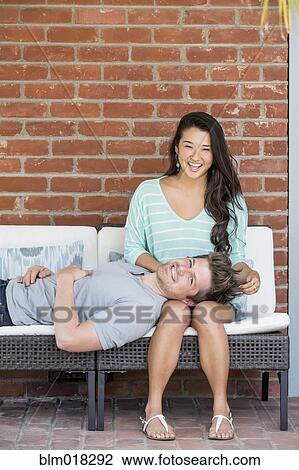Stock Image - Couple relaxing together on bench. Fotosearch