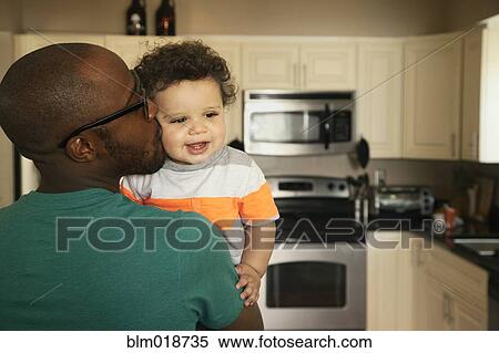 Stock Photography - Father kissing baby in kitchen. Fotosearch