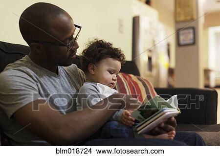Picture - Father reading to baby on sofa. Fotosearch