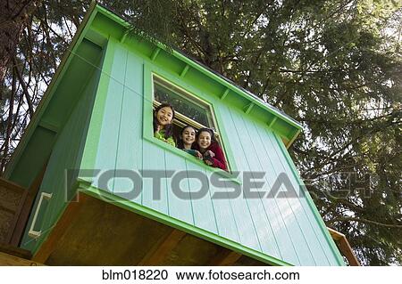 Stock Image - Girls leaning out tree house window. Fotosearch