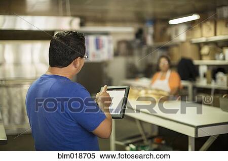 Hispanic baker using tablet computer in kitchen View Large Photo Image Stock Photography - Hispanic baker using tablet computer in kitchen. Fotosearch