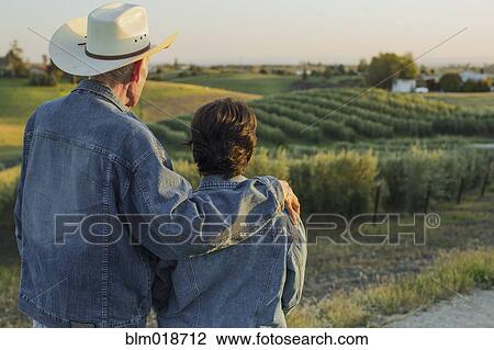 Stock Image - Hispanic farmers standing in vineyard. Fotosearch