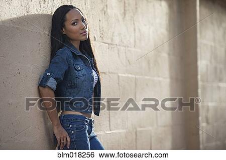 Hispanic woman leaning against wall View Large Photo Image Stock Photograph - Hispanic woman leaning against wall. Fotosearch