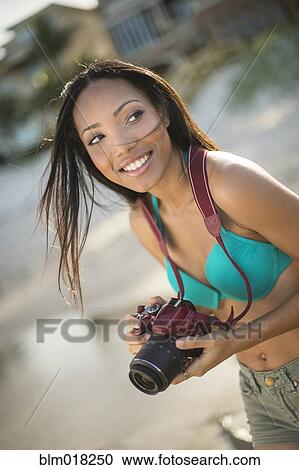 Stock Image - Hispanic woman taking pictures outdoors. Fotosearch