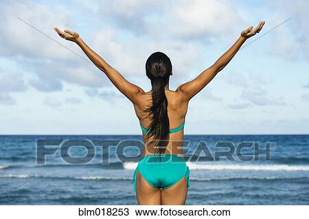 Stock Image - Hispanic woman wearing bikini on beach. Fotosearch