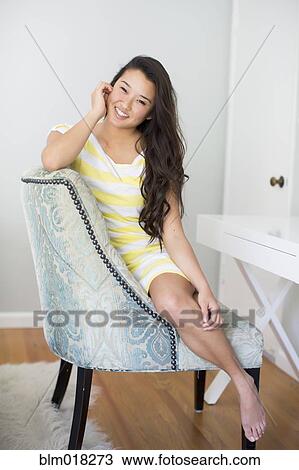 Stock Image - Japanese woman smiling in armchair. Fotosearch